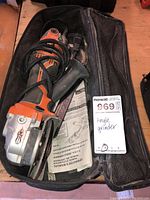 Ridgid orange and black angle grinder inside a black mesh zippered carrying case with a power cord wrapped around the tool. Shows signs of wear and dirt on the case.