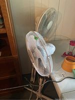 Two white pedestal fans with adjustable heights, one branded OCEAN visible on the grill, both untested