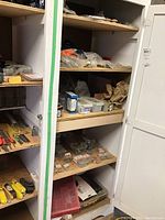 Photo showing shelves stocked with various hardware items including nails, screws, knobs, and blades in plastic packaging and boxes.
