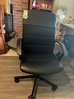 Front view of the black swivel office chair showing padded armrests, mesh and faux leather upholstery, and caster wheels base.