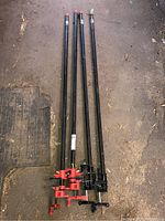 Four pipe clamps lying on the floor, showing the full length of the clamps.