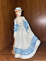 Front angle showing full figure in blue and white dress with hat and broom.
