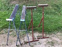 Front angle showing the pair of folding saw horses and the pair of red rollers on grass surface.