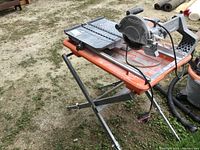 Full view of Ridgid wet tile saw mounted on stand outdoors, showing base and blade.