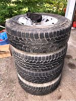 Stack of 4 Hankook winter tires with silver alloy rims, tires show dirt and wear.