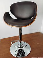 Front view of the adjustable bar stool showing brown cushioned seat and curved design with chrome base