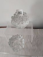 Pair of clear glass Kosta Boda candle sticks on a white surface, showing bubble texture and opening for candle.