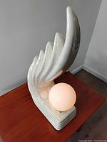 Three-quarter view of lamp showing wave-shaped ceramic fins, stepped base, and frosted globe