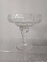 Front view of the clear footed comport showing textured glass bowl with ribbed rim and multi-tiered stem.