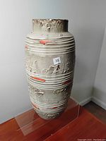 Front view of tall ceramic vase with rough texture and orange accents, showing overall condition and size.