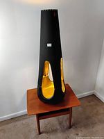 Full view of tapered lamp on small wooden table, showing overall form, height and color contrast