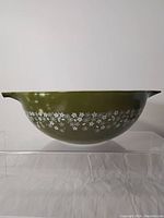 Front view of large green Pyrex mixing bowl showing white floral pattern and spout