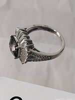 Side view of the sterling silver ring showing central purple gem and baguette cut stones with detailed shank.