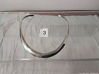 Top view of silver collar necklace showing tapered design and smooth surface.