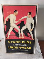Front of the white box featuring vintage graphic label showing two men in white full-body underwear and the brand 'Stanfield's Unshrinkable Underwear'.