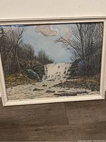 Frontal photo of the framed watercolour and ink painting showing waterfall and surrounding landscape.
