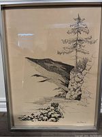 Framed landscape drawing showing a tall tree on rocky shore and water with hills in the background.