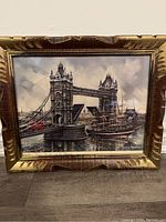 Framed print artwork of Tower Bridge with a ship and a red bus visible, showing the overall lot condition.