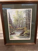 Framed lithograph depicting a nature scene with trees, stream, and rocks.