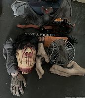 Top view showing multiple Halloween decorations including severed head prop, large hand glove, spider web with round black light bulb, and fake spiders and bats.