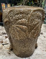 Textured ceramic elephant garden seat side view showing porous surface and overall shape.