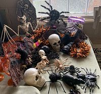 Overall table view showing a variety of Halloween items including skulls, bats, spiders and orange plastic wine glasses.