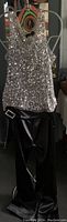 Full view of a women's silver sequin sleeveless top paired with black satin slacks featuring a rhinestone buckle sash.