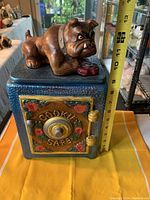 Front view of vintage Makers Mark ceramic cookie safe in blue with detailed floral design on door and bulldog figurine on top showing size with measuring tape