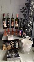 Overall lot showing six Marilyn Monroe wine bottles, plexiglass ice bucket, party trays, invitations, sequined bottle stoppers, bottle opener, and plastic stem wine cups.