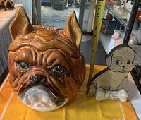 Front view of large ceramic bulldog cookie jar beside wooden dog plaque