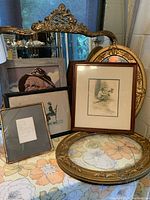 Overview of all vintage and antique framed art pieces with large ornate mirror behind
