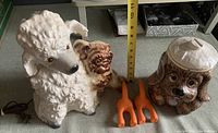 Front and side views of the vintage ceramic poodle and pug TV lamp, begging puppy dog cookie jar, and orange dog butt leash holders with measuring tape indicating size.