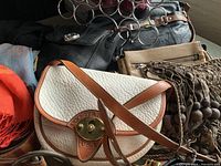 Close-up of Dooney & Bourke cream and brown leather purse with signature logo plate.