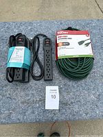 Photo showing the three black power strips and the green 100-foot extension cord on blue surface.