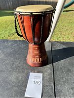 Front view of the African djembe drum showing carved wooden base, rope tuning, and natural skin head.