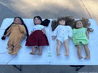 Four dolls on a table showing overall condition and look: two American Girl and two Pleasant Company dolls.