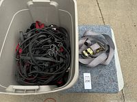 Large plastic bin filled with numerous black and red bungee cords.