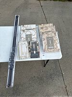 Full view of metal curtain rod and packaged curtain panels with tags, all items grouped on a white table outdoors.