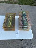 Five boxed sets of garden string lights displayed on a white table, three with copper color wire spheres and two with brown wire spheres.
