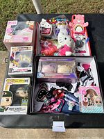 Overview of toy lot showing boxed Funko Pop! figures, Hello Kitty light, Care Bears plush, aromatherapy bath bombs, and assorted smaller items.