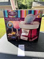 Front view of the Nostalgia Electrics Hard & Sugar-Free Candy Cotton Candy Maker boxed showing vibrant packaging with images of cotton candy and product features.