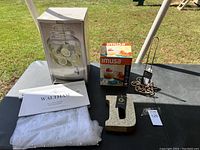 Overview photo showing all items on table including beverage dispenser box, Imusa kitchen item box, letter 'J', metal loop tool, and Waltham curtain with paperwork.