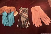 Three pairs of women's gloves: turquoise with faux fur cuffs, brown and gray plaid, and solid pink