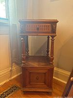Full front view of antique French commode showing wood carvings, top drawer, middle shelf, and bottom cupboard.