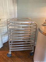 Full view of the aluminum baker's rack with multiple slotted rails and caster wheels