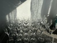 Full set of 24 clear wine glasses arranged in four rows.