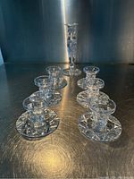 Photo showing entire set of one tall and six short crystal candlestick holders arranged on metallic surface.