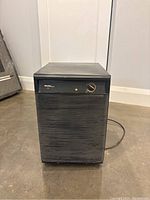 Front view of the black Danby dehumidifier showing horizontal slats, rotary dial, and power cord coiled behind.