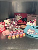 Photo shows the entire Hello Kitty collection including book, lunch box, plush toy, two small bags, several heart-shaped tins, a card, and a post-it sticker set.