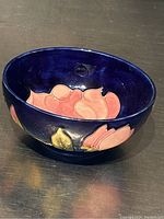 Side angle showing the bowl's cobalt blue interior with pink magnolia flower and yellow leaf decoration